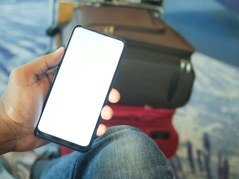 Traveler holding phone with luggage at the airport