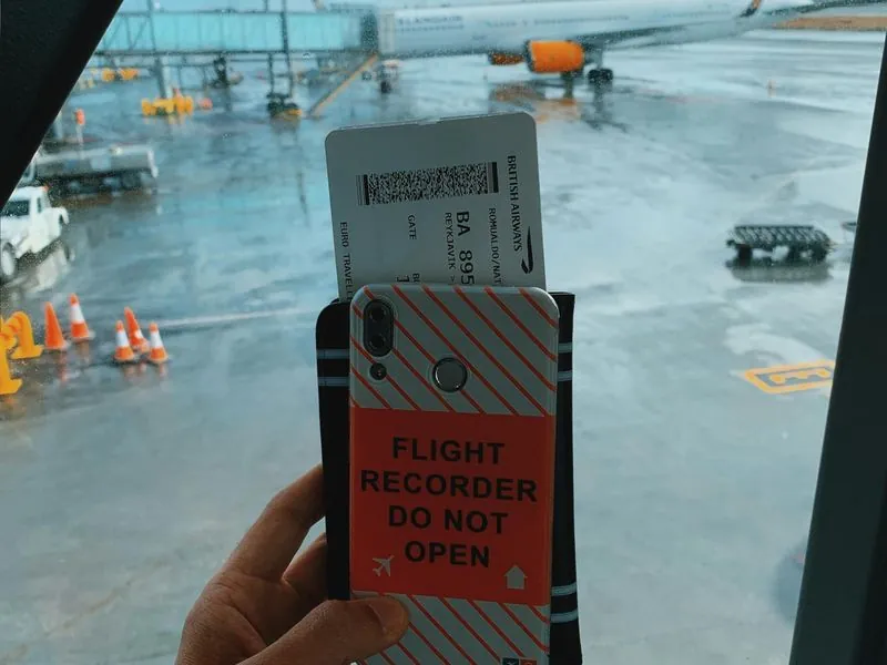 Close-up of boarding pass and phone at the gate window